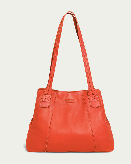 The Ada Triple Entry Tote by American Leather Co. is a square-shaped, radiant red smooth leather bag with two long shoulder straps, detailed stitching, and a small embossed logo on the front. It stands out perfectly against a light cream backdrop, ideal for carrying everyday essentials.