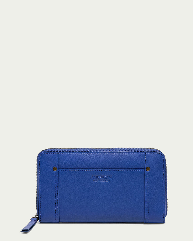 The Austin Continental Wallet with RFID from American Leather Co. is a blue leather zip-around wallet featuring a subtly textured surface, two vertical stitch lines, and small rivets on each side. The brand name "AMERICAN" is embossed in the center. Complete with a matching blue zipper pull and RFID protection, it ensures both style and security.