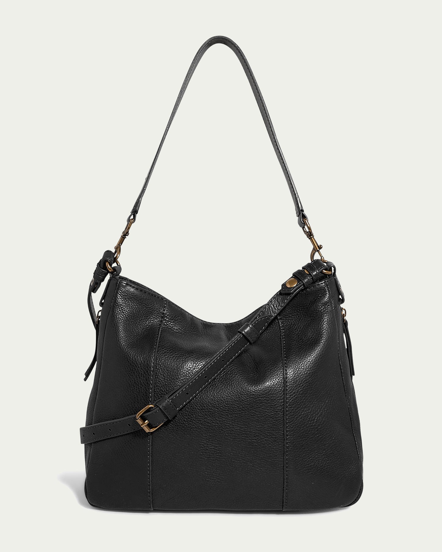 The Austin Convertible Shoulder Crossbody by American Leather Co. is a black leather shoulder bag with a slouchy shape. It features a shoulder strap, an additional adjustable crossbody strap, and gold hardware like buckles and clips. Shown against a light background, it includes side zipper pockets for added convenience.