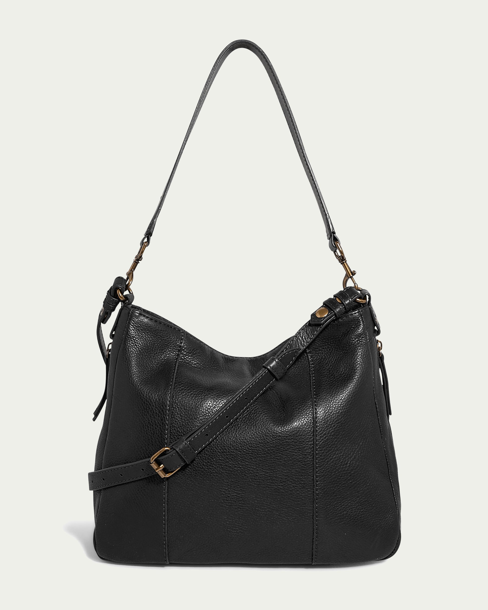 The Austin Convertible Shoulder Crossbody by American Leather Co. is a black leather bag with a hobo design. It features a single shoulder strap and an additional adjustable strap with brass buckle details, as well as zipper pockets, a textured surface, and a relaxed, slouchy shape.