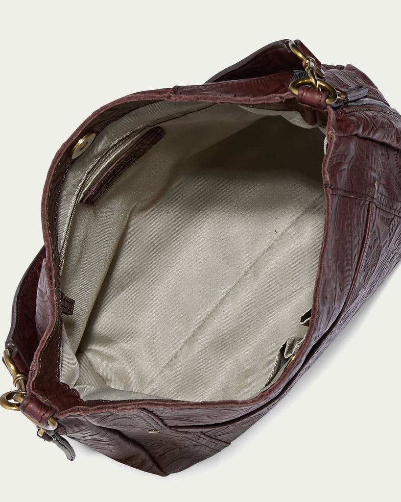 A top-down view of the Austin Shoulder handbag from American Leather Co. reveals its beige lining. Crafted from luxurious American leather, this casual accessory features a zippered side pocket and small open compartments for organization, while gold-tone hardware on the edges adds a touch of elegance.