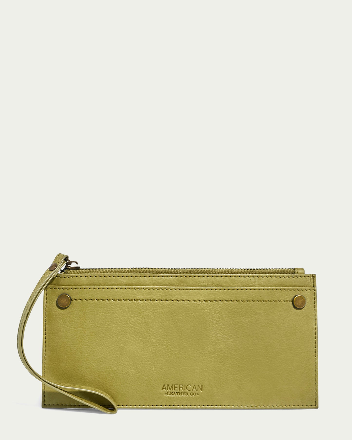 The Bristow CC Zip Wallet Wristlet with RFID by American Leather Co. is a slim accessory crafted from light green leather. It boasts a sleek silhouette and comes with a convenient wrist strap. The clutch is adorned with two metal button accents and stitched detailing on the front, and it features "American Leather Co." embossed at the bottom center.