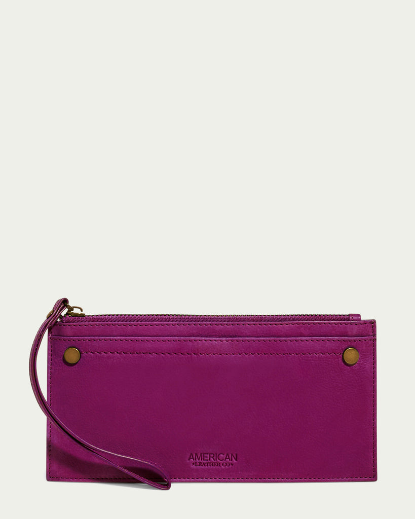 Introducing the Bristow CC Zip Wallet Wristlet with RFID by American Leather Co. - a sleek, purple leather accessory showcasing a slim silhouette. This stylish wristlet features a convenient strap on the left side and is adorned with two brass rivets at each top corner. The brand name "American Leather Co." is elegantly embossed at the bottom center, all set against a plain white background.