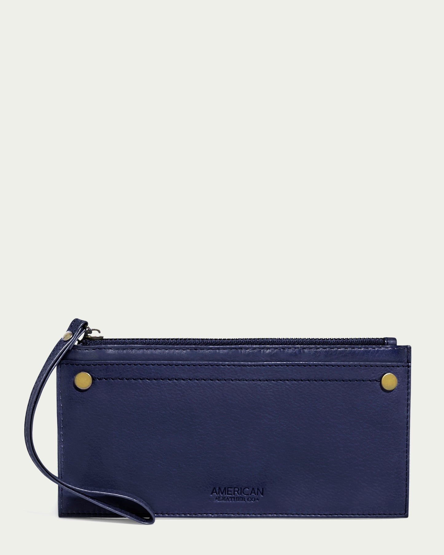 The Bristow CC Zip Wallet Wristlet with RFID from American Leather Co. is a slim wallet wristlet crafted in navy leather, adorned with gold button accents and a convenient wrist strap. Its sleek silhouette is highlighted by the word "American" embossed on the front, reflecting its proud American Leather Co. heritage. For added convenience, it features a zippered compartment on the top edge.