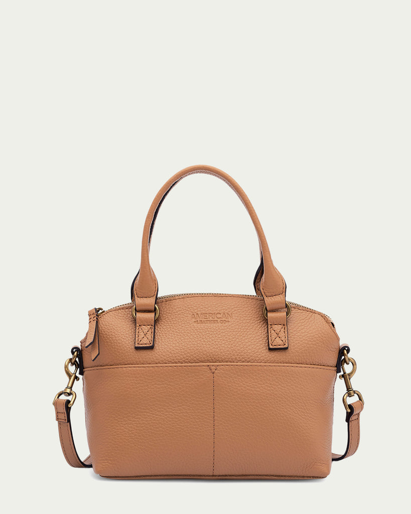 Introducing the Carrie Mini Dome Crossbody by American Leather Co.: a Vachetta Pebble genuine leather handbag with two short handles and a detachable shoulder strap. Adorned with gold hardware and a small embossed logo, it features a textured finish, multiple pockets for organization, and a secure zipper closure on top.