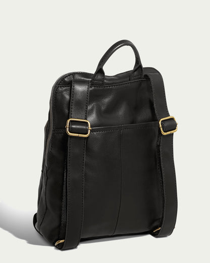 The Cleveland Backpack from American Leather Co. is a sleek, black, buttery-soft leather backpack featuring two adjustable back straps and gold buckle accents. This genuine American leather backpack includes a top handle and a convenient back pocket. The side zippers provide easy access to the main compartment, and it is showcased against a neutral light background.