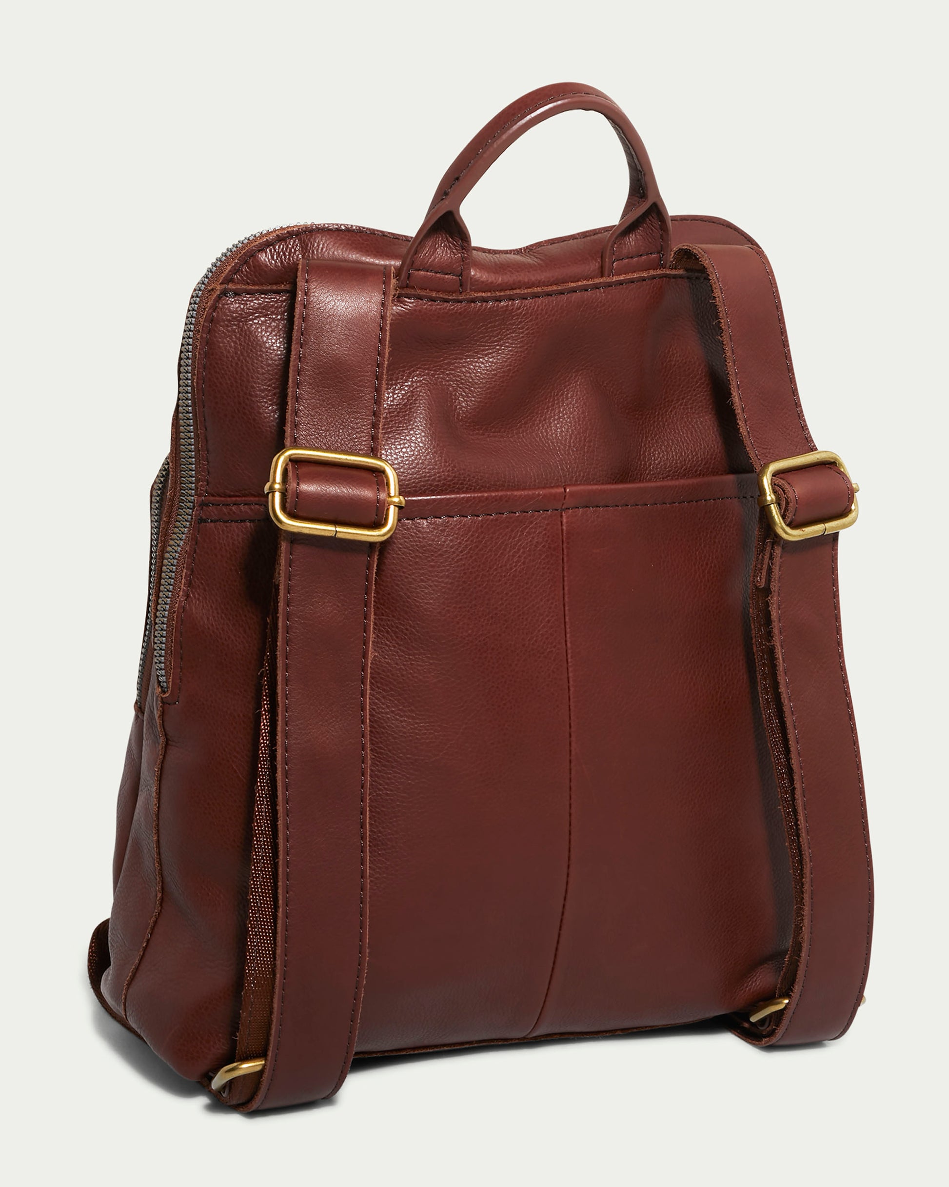 The Cleveland Backpack by American Leather Co. is a brown leather purse with antiqued hardware, gold-tone buckles, adjustable straps, and a top handle. Made from genuine leather with a smooth texture, it features a zippered main compartment and is shown from the back.