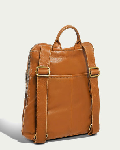 Introducing the Cleveland Backpack by American Leather Co., a backpack crafted from buttery soft genuine American leather, featuring adjustable straps and a top handle. Its sleek design includes visible stitching and a side zipper, perfectly contrasting with the plain light background.