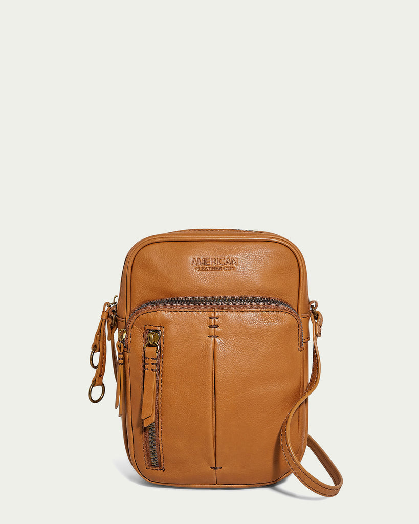 The Cleveland NS Crossbody is a brown leather bag made from genuine American leather, designed with several zippered pockets and an easy-to-use shoulder strap. The front showcases the embossed brand name "American Leather Co." on a simple light background.