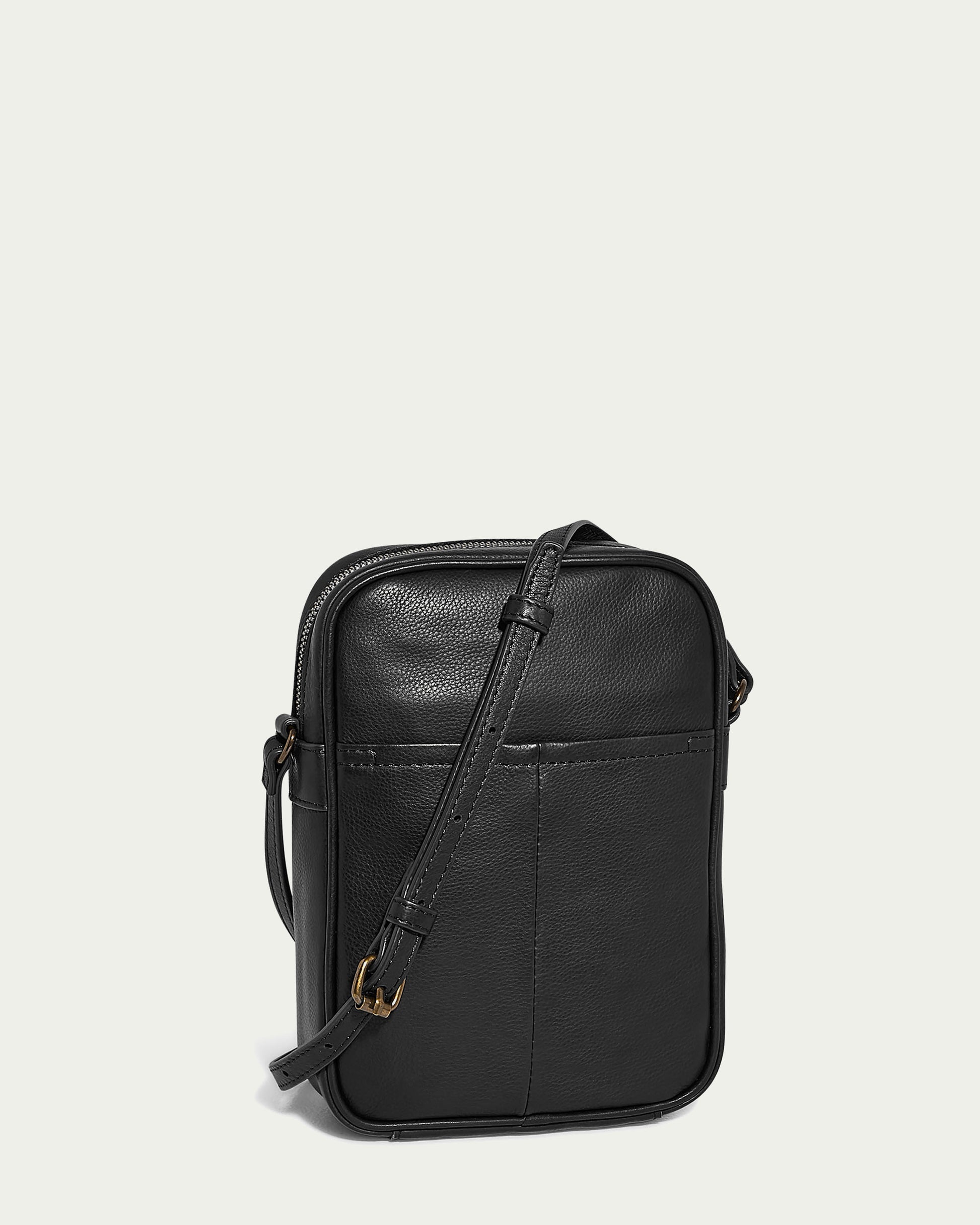 The Cleveland NS Crossbody by American Leather Co. is crafted from Genuine American Leather, boasting a black leather exterior, a front pocket, gold-tone buckle accents, and an adjustable crossbody strap. This sleekly designed bag with a top zipper closure stands against a plain, light-colored background.