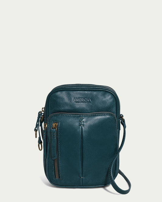 The Cleveland Large NS Crossbody by American Leather Co. in teal is made from genuine leather and includes a front zipper pocket and adjustable strap, set against a plain light background.