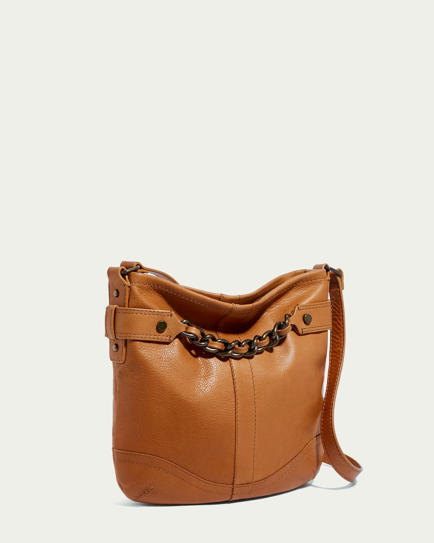 The Elton Crossbody by American Leather Co. is a tan leather shoulder bag with antiqued hardware, featuring a chain-link strap and side buckle. It stands against a plain white background, highlighting its sleek design and textured finish made from genuine American leather.