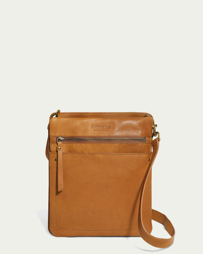 Explore the Lily Multi Compartment Crossbody by American Leather Co., made from genuine leather. This stylish light brown accessory includes a zippered front pocket and adjustable strap, ideal for any occasion. Its elegance stands out against a plain white background.