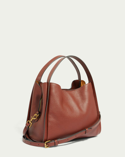 The Auburn Triple Compartment Convertible Crossbody from American Leather Co. is displayed against a plain background. Crafted from genuine brown leather with a pebbled texture, the handbag features a structured design with two sturdy handles and an adjustable, detachable shoulder strap adorned with gold-tone hardware. The interior of the bag is partially visible.