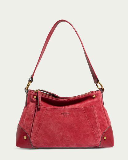 The Becket Triple Entry Shoulder from American Leather Co. is a stylish red suede shoulder bag featuring a matching leather strap and trim made of Genuine Leather. The bag boasts decorative stitching, brass hardware, and a zip closure. It includes a small exterior pocket, subtle branding embossed on the front, and a triple entry design for added convenience.