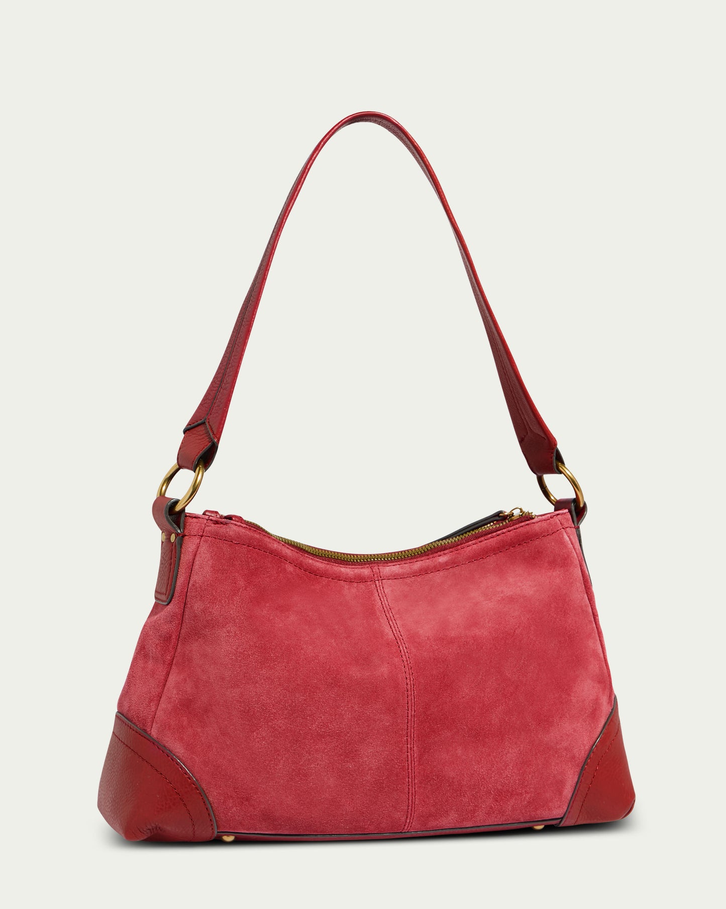 The Becket Triple Entry Shoulder by American Leather Co. is a stylish handbag crafted from genuine soft red suede with darker leather accents on the corners. This traditional shoulder bag features a single strap, gold-tone hardware, and a top zipper closure. Its simple and elegant design makes it perfect for both casual and formal use.