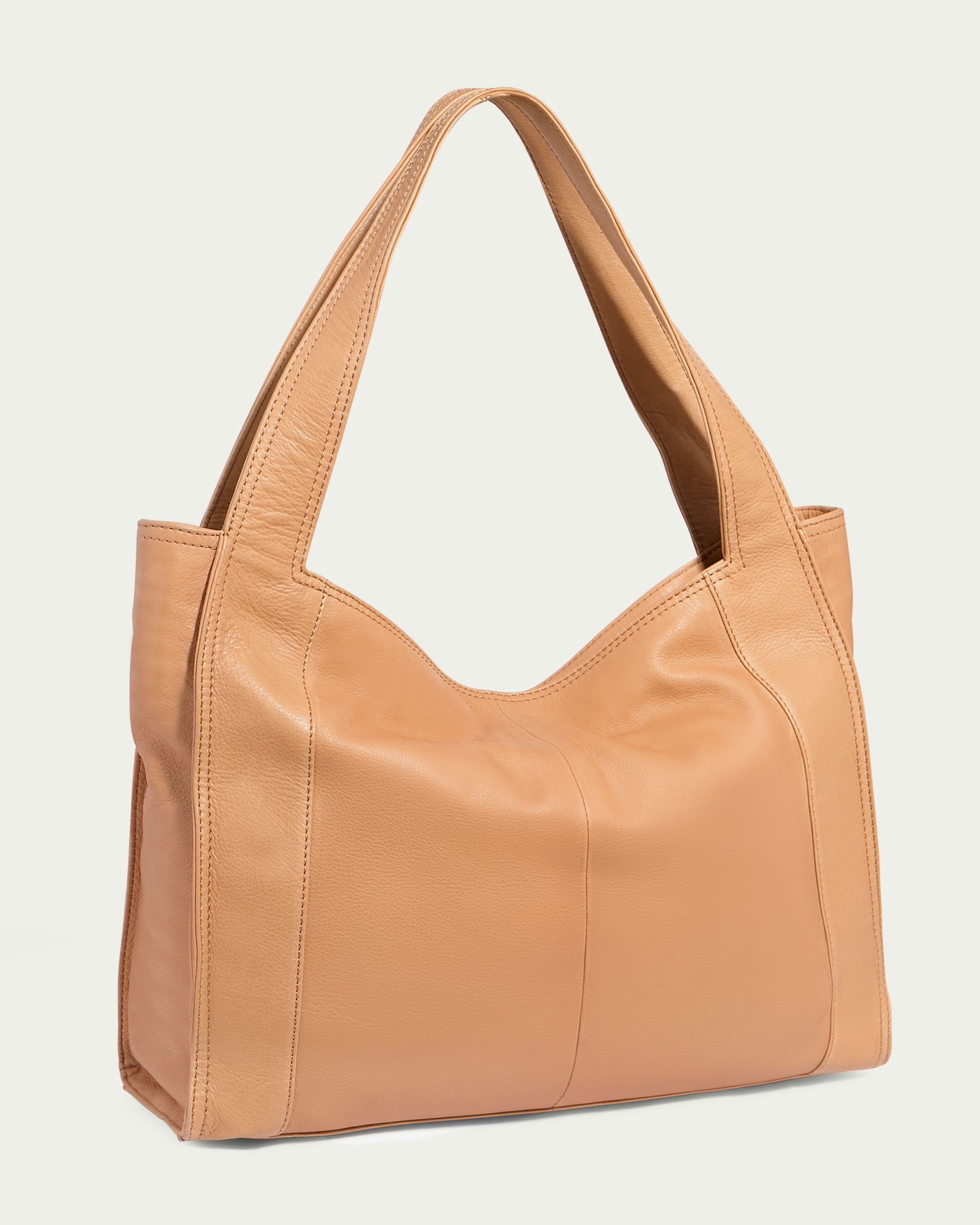 The Plymouth Ziptop Tote by American Leather Co. is a tan leather tote bag crafted from genuine leather, featuring a wide handle. It boasts a smooth texture and visible stitching that lends it a structured yet soft appearance. The design includes a zipper pocket for added functionality, all set against a light, neutral background.