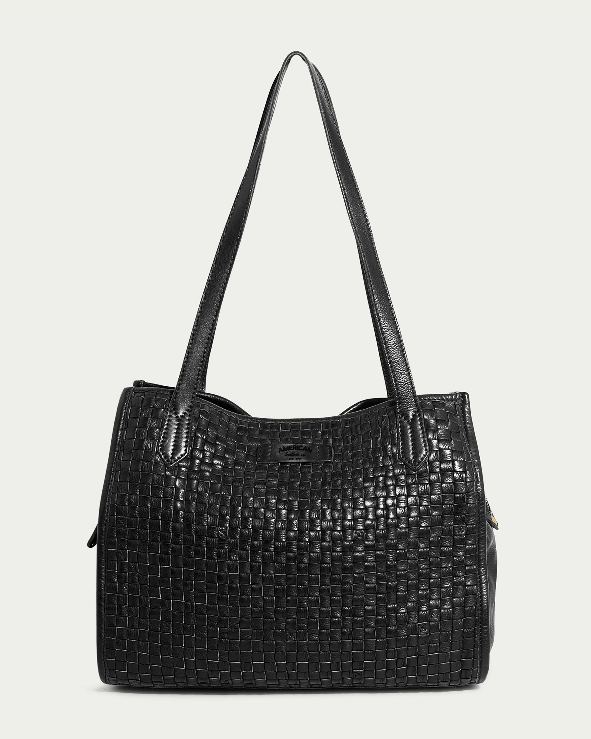 A black Sandy Woven Triple Entry Satchel with double shoulder straps, part of the American Leather Co. collection. The bag features a textured pattern on the front and a smooth leather finish on the sides. It has a rectangular shape and appears to be made of genuine leather or a similar material.