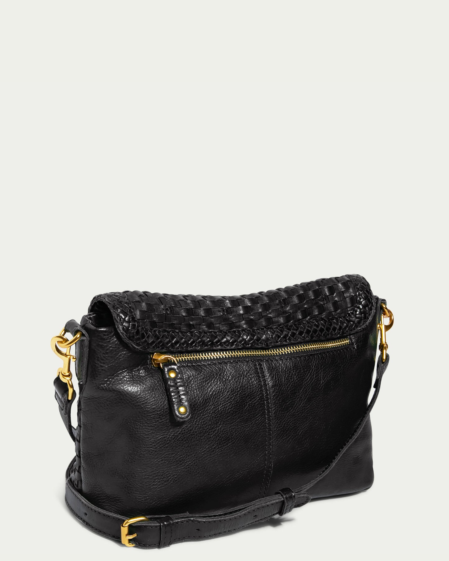 Introducing the Summers Woven Crossbody by American Leather Co.—a sleek and stylish black leather handbag featuring a woven flap design, gold hardware, and an adjustable shoulder strap. The front boasts a small zippered pocket accented with three metallic studs. This limited edition piece is perfect for versatile use as a crossbody bag.