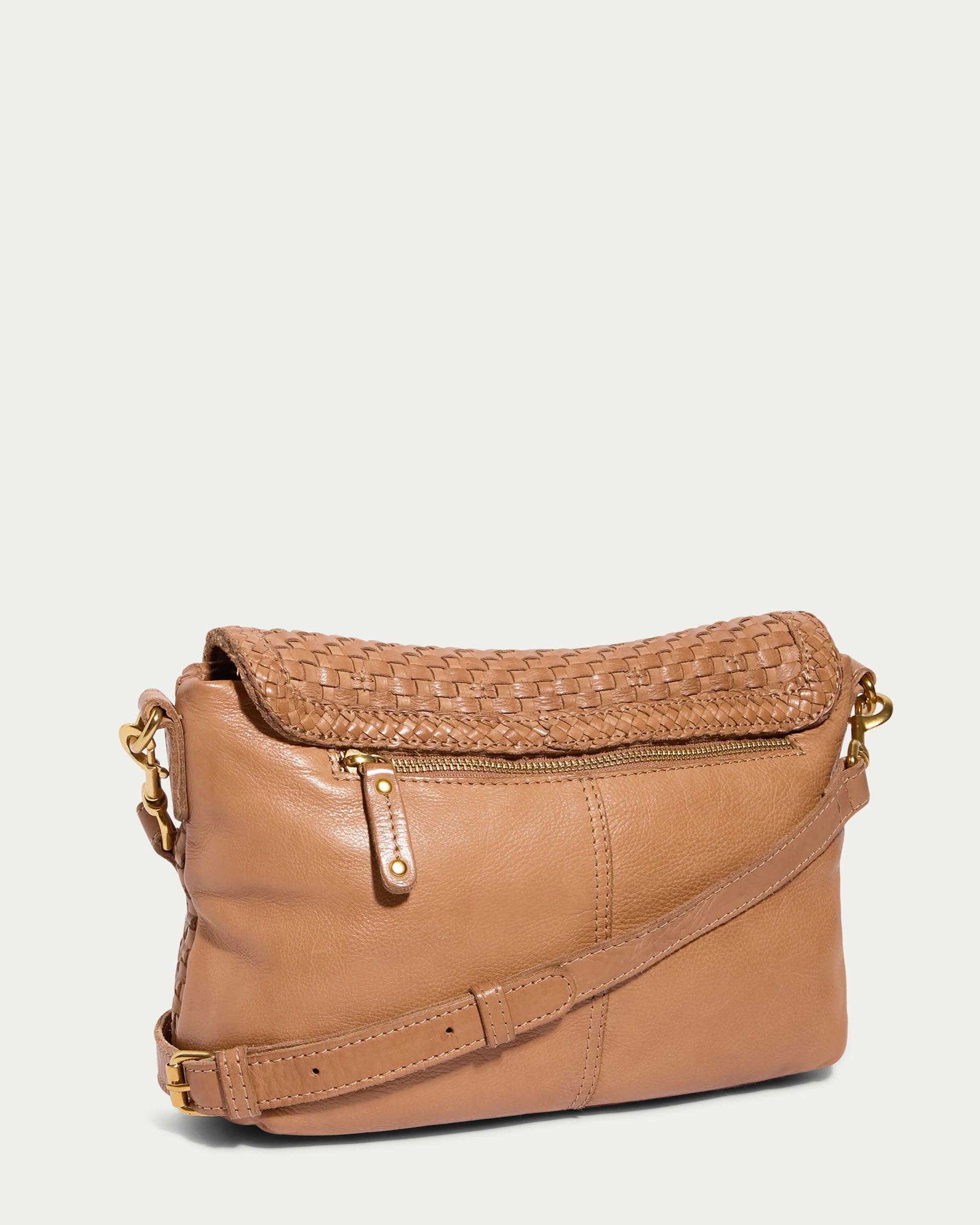 The Summers Woven Crossbody by American Leather Co. is a light brown handbag with a genuine leather crossbody strap and a woven flap. Featuring stitching details, a small vertical zipper pocket on the front, gold-tone hardware, and a simple, elegant design, it stands out against a plain light beige background.