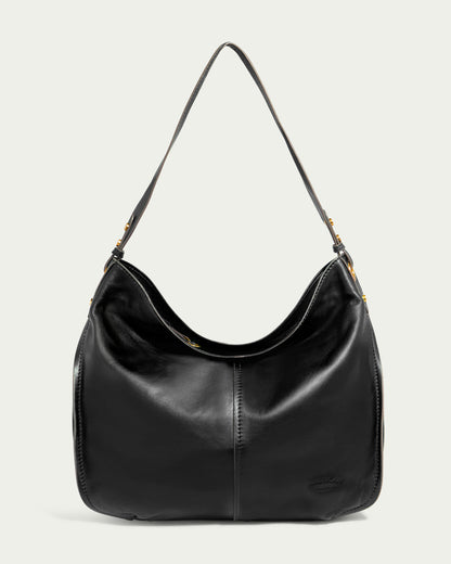 The Summit Large Top Zip Hobo by American Leather Co. is displayed against a light background. This black leather shoulder bag showcases a sleek, minimalist design with a comfortable, adjustable strap and subtle stitching details. Crafted from genuine leather, it features a spacious main compartment with a zipper, making it perfect for everyday use.