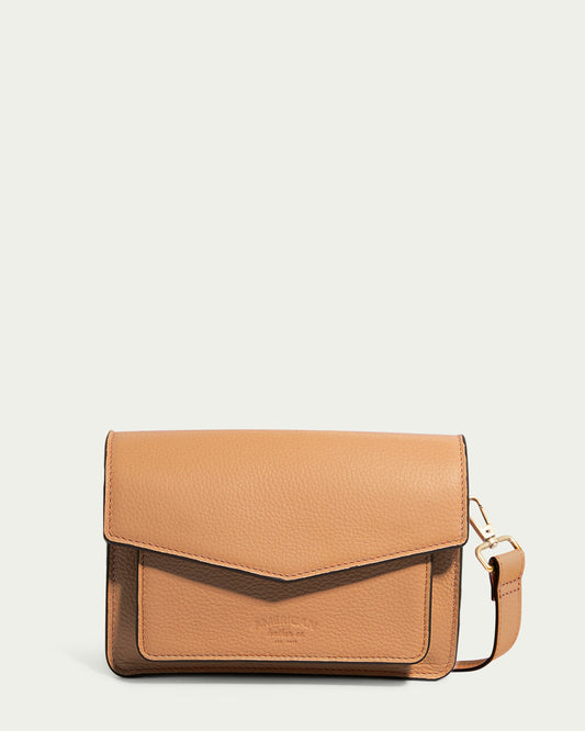 The Troy Acordian Crossbody from American Leather Co. is a tan leather bag made from genuine, weatherproof leather with a textured finish. It boasts a flap closure and a detachable strap, elegantly displayed against a light background.