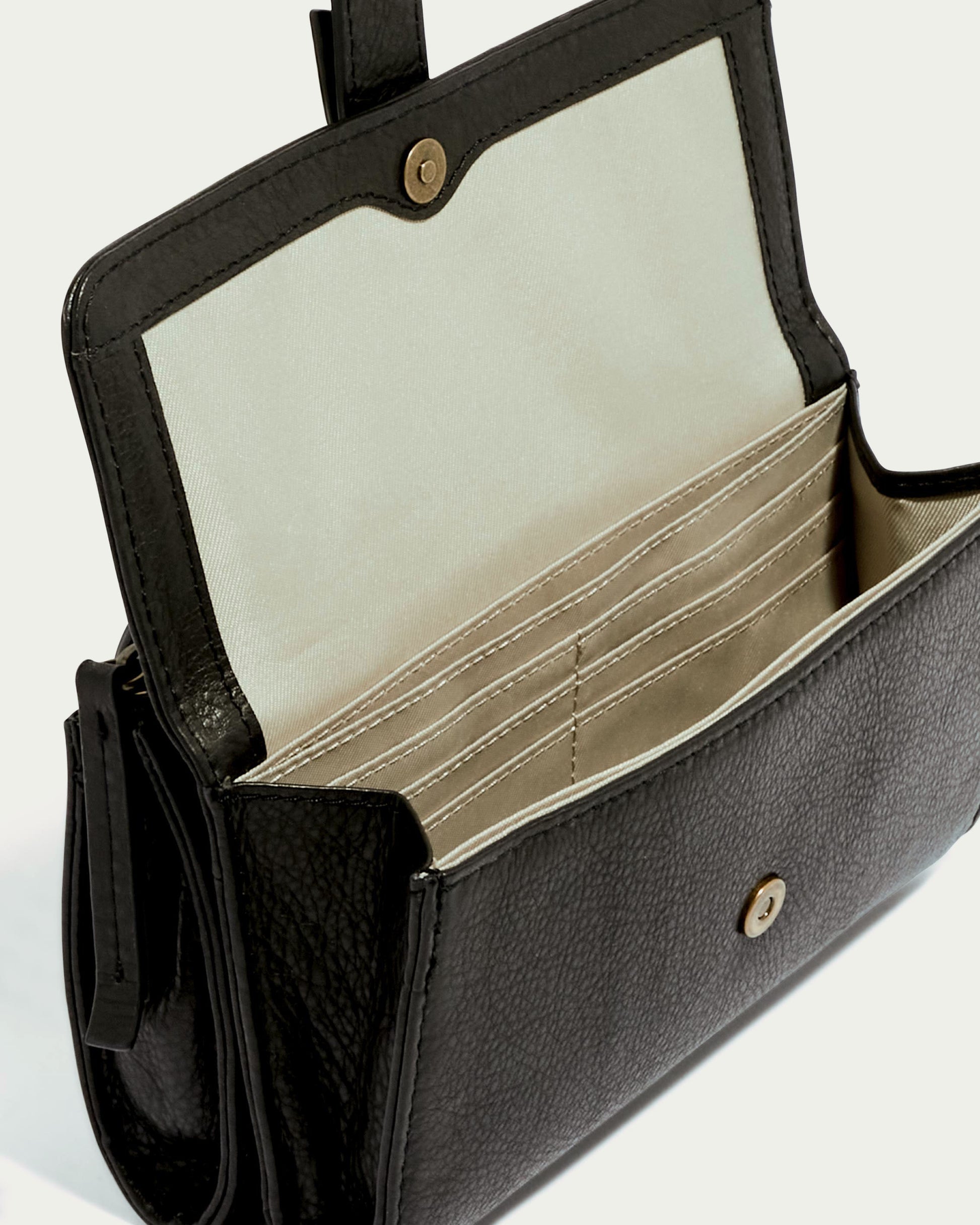 The Essex Wallet Crossbody by American Leather Co. features a sleek black exterior crafted from genuine American leather and a beige interior with multiple card slots and compartments. Its versatile design includes an optional adjustable crossbody strap for hands-free convenience, set against a neutral background.