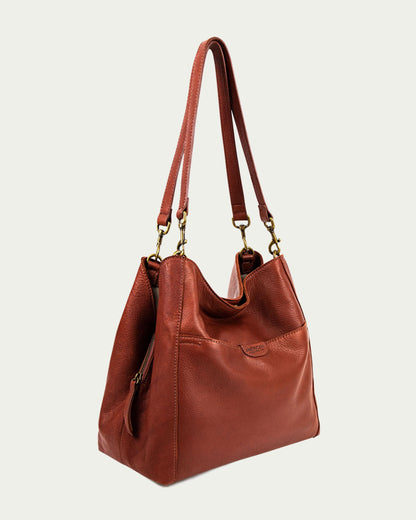 The Austin Triple Entry Hobo by American Leather Co. is a brown, genuine leather bag with two long handles and gold hardware. Its slouched design and textured surface make it a stylish yet casual accessory for any occasion.