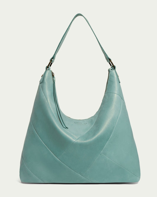 The Cobb Large Hobo by American Leather Co. is a stylish turquoise leather bag, featuring a spacious compartment and a comfortable strap for shoulder carrying. Made from genuine glove leather with minimal stitching and a smooth finish, it has a sleek and elegant look.