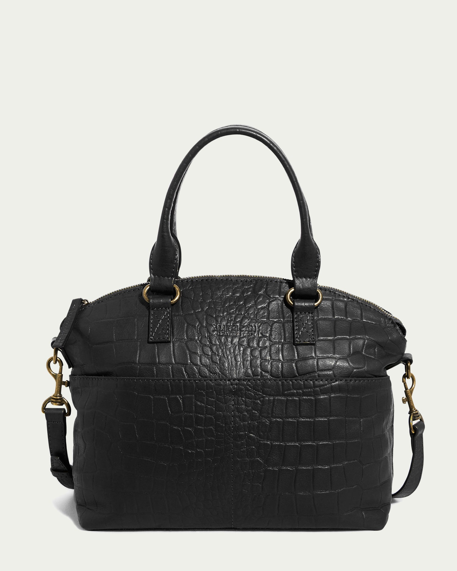 The Carrie Dome Satchel by American Leather Co. is made from genuine American leather featuring an elegant crocodile texture. It includes two short handles and a gold hardware-accented adjustable crossbody strap. The bag's design is structured with a rounded top and a secure zip closure.