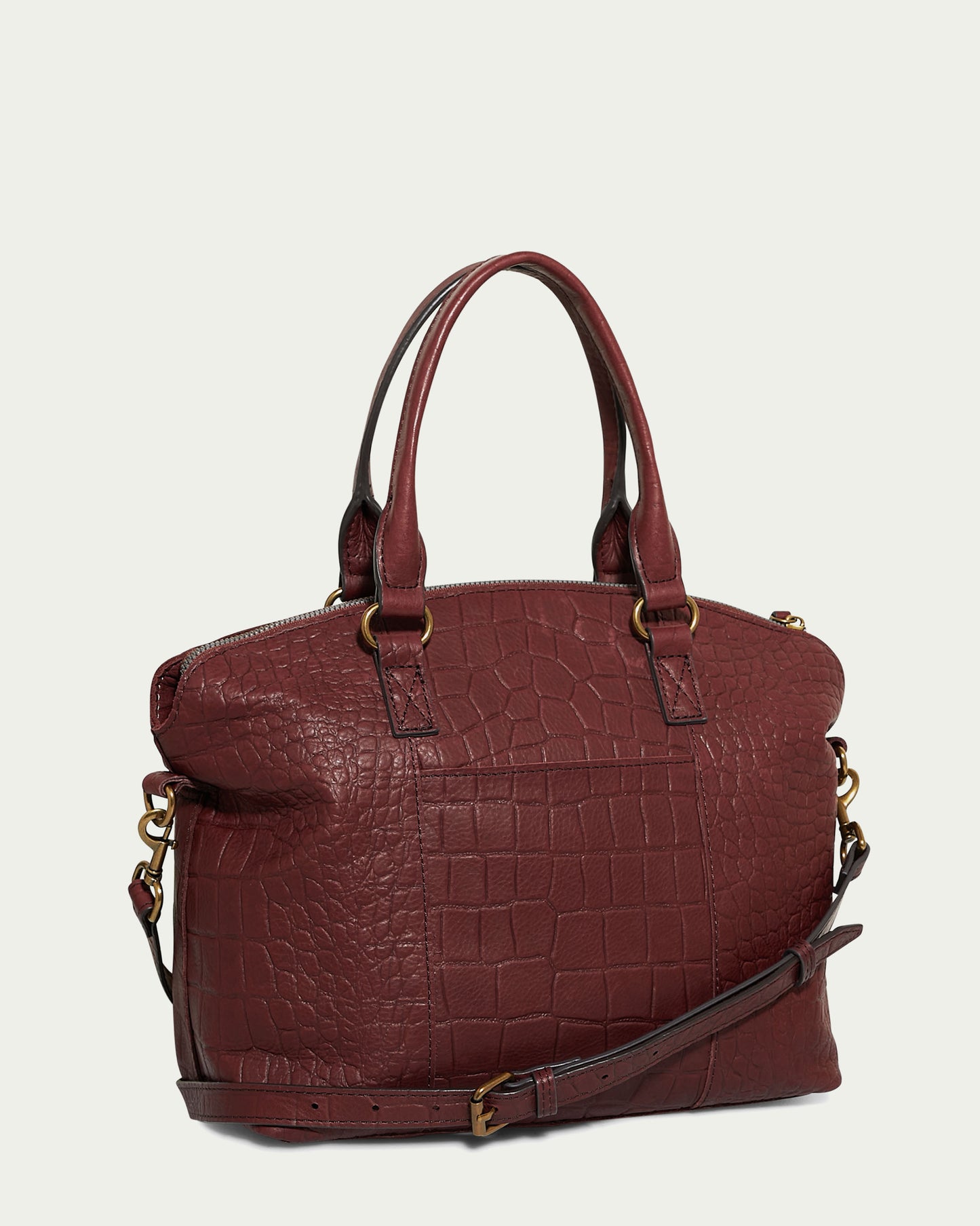 The American Leather Co. Carrie Dome Satchel is a chic maroon handbag featuring genuine leather with a crocodile pattern, sturdy handles, an adjustable crossbody strap, gold-tone hardware, a zippered top closure, and a spacious design for style and functionality.