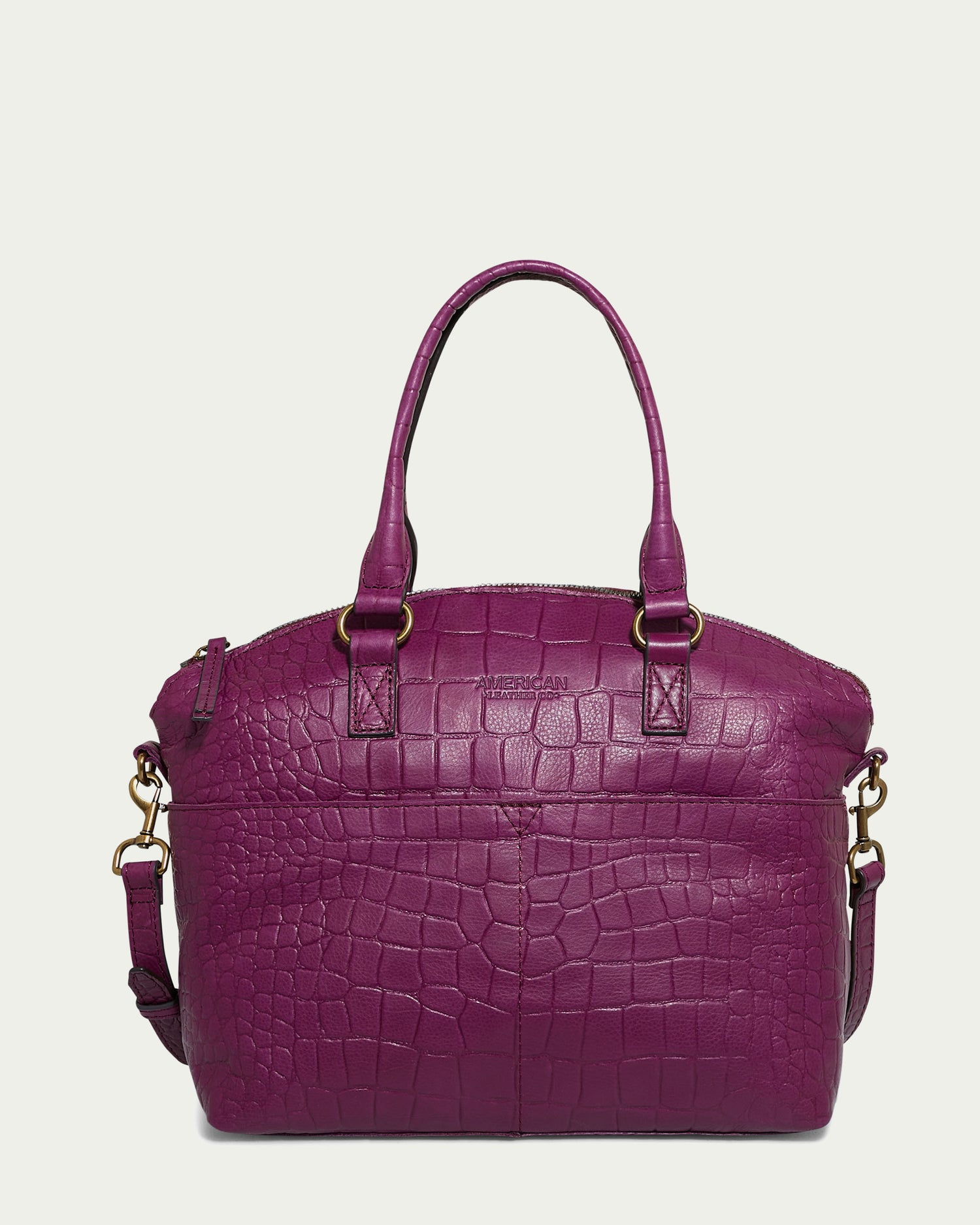 The Carrie Dome Satchel by American Leather Co. is a purple leather bag with a crocodile pattern, made from genuine American leather. It features gold hardware, two handles, and a detachable shoulder strap, along with a zip closure, all displayed against an off-white background.