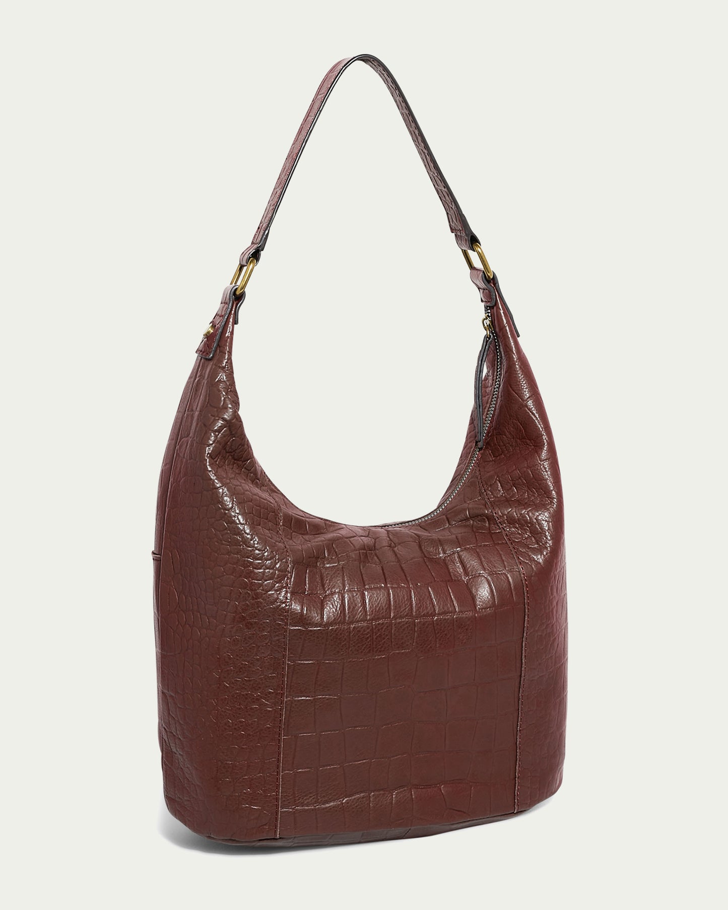 The Carrie Hobo by American Leather Co. is a stylish brown shoulder bag featuring a crocodile pattern design. Made from high-quality American leather, it includes a single adjustable strap and a spacious main compartment. The bag's texture and sheen catch the light beautifully, highlighting the intricate details of the pattern.