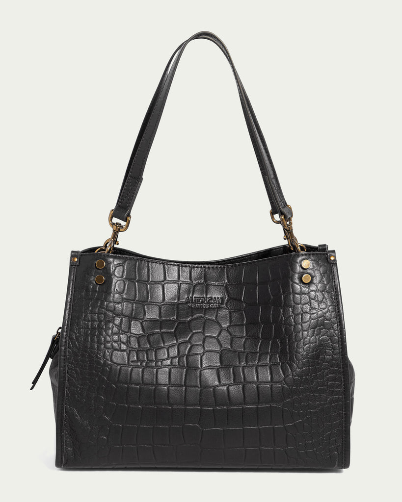 Presenting the Lenox Triple Entry Satchel by American Leather Co. – a sleek, black satchel crafted from textured leather with an exquisite crocodile skin pattern. This everyday essential showcases gold-tone hardware and dual shoulder straps for effortless carrying. Additional features include a small zippered side compartment and subtle branding on the front, ensuring both style and functionality.