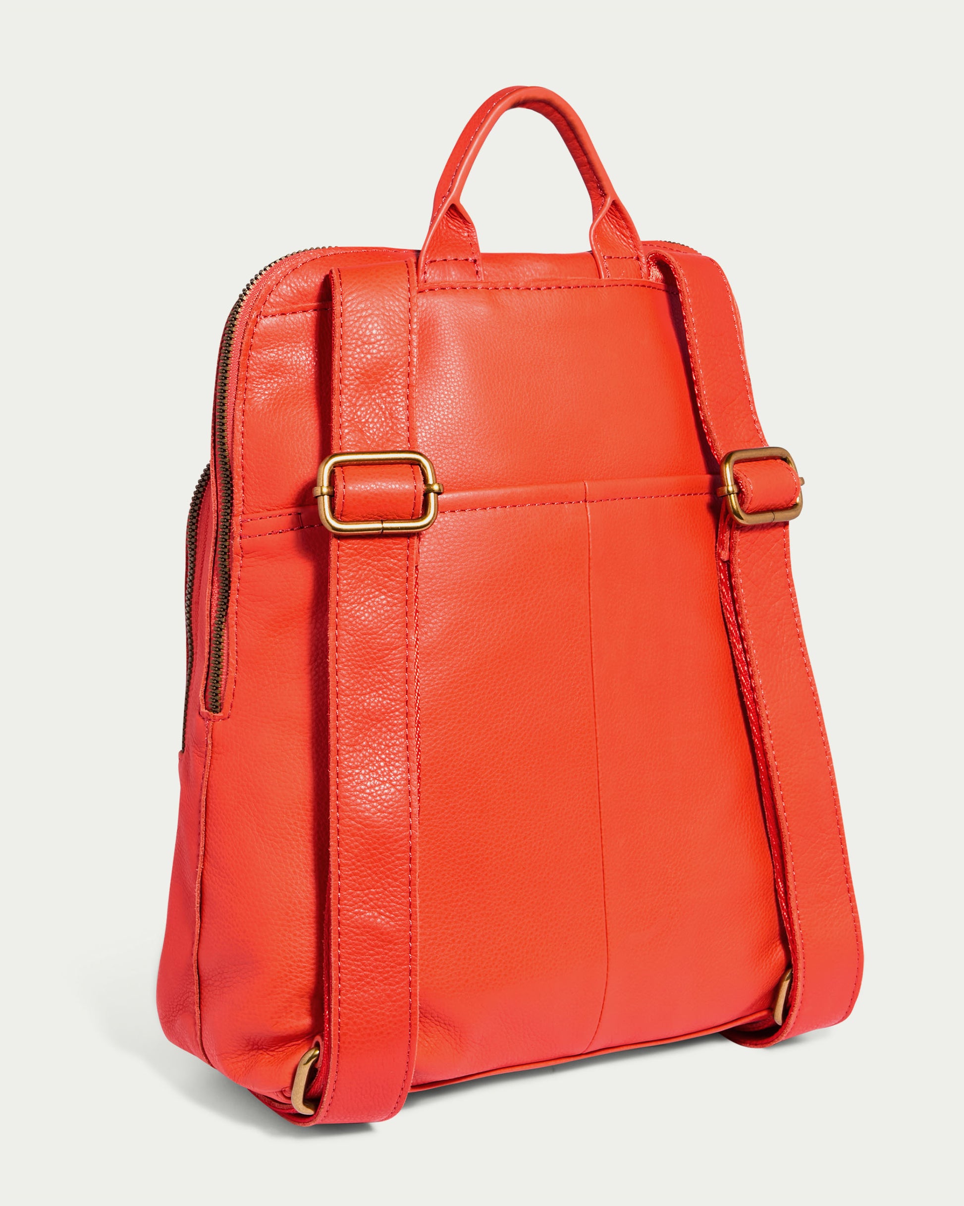 The Cleveland Backpack by American Leather Co. is presented from the back, showcasing its vibrant red leather with adjustable straps and brass buckles. It features a top handle and a central pocket at the rear, highlighting its genuine leather craftsmanship against a plain light background.