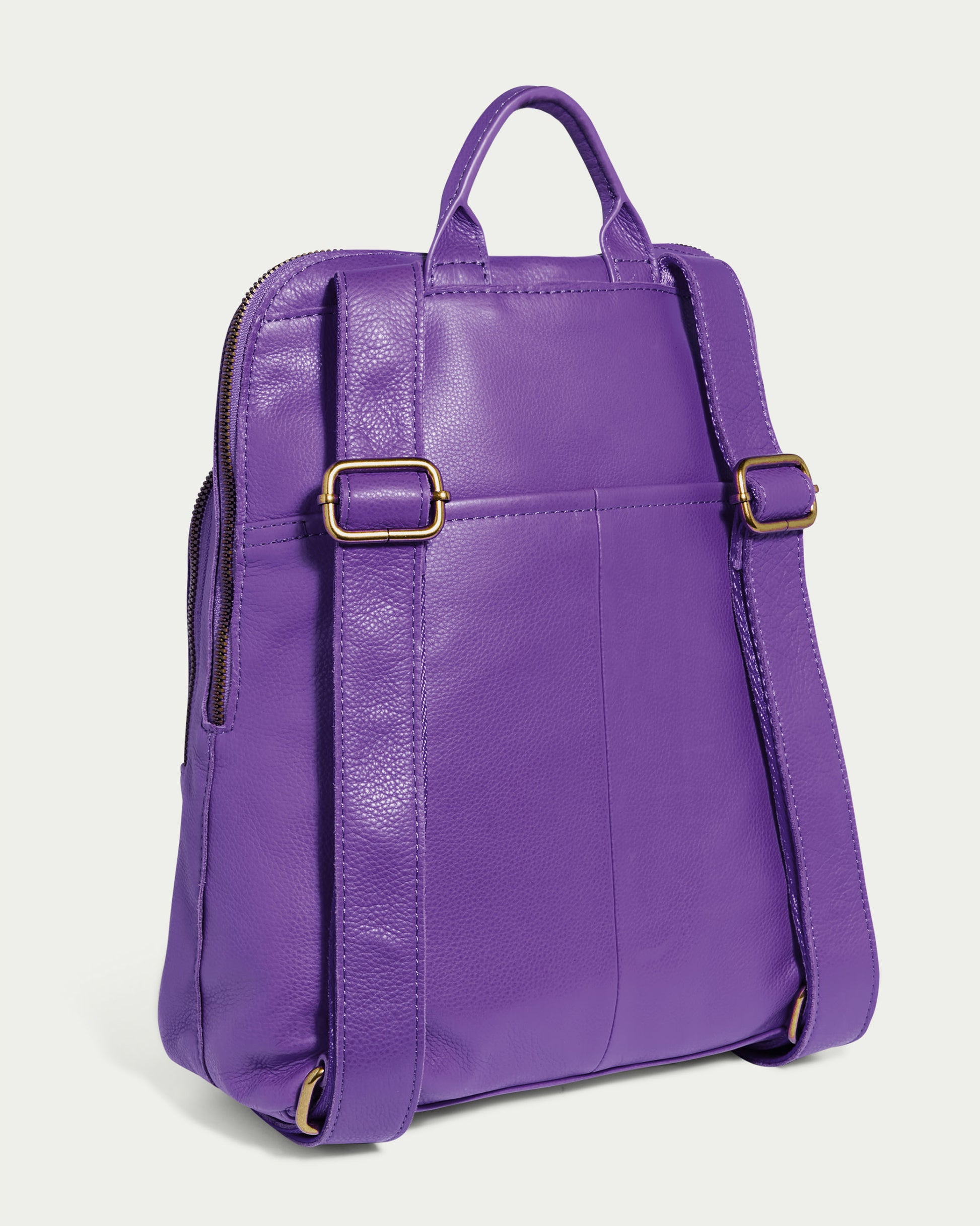 The Cleveland Backpack by American Leather Co. is a stunning purple leather purse made from genuine leather, boasting adjustable back straps and gold-tone buckles. It features a top handle and a back pocket, all set against a plain background.