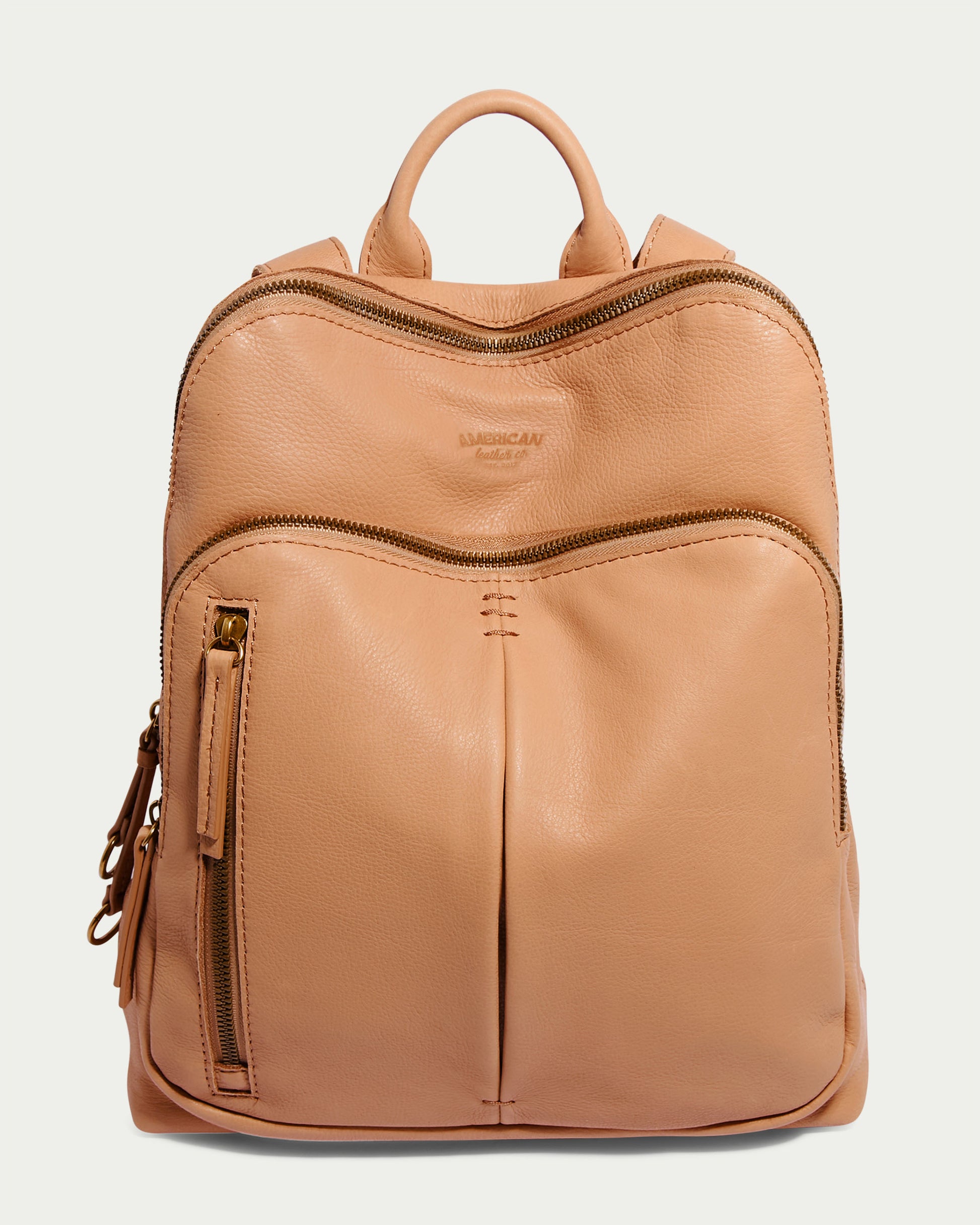 Introducing the Cleveland Backpack by American Leather Co., a nutmeg leather backpack purse that embodies a minimalist design. It comes equipped with a front zip compartment, top handle, and two shoulder straps. Made from genuine leather, this backpack flaunts a smooth texture with visible stitching for an elegant and polished look.