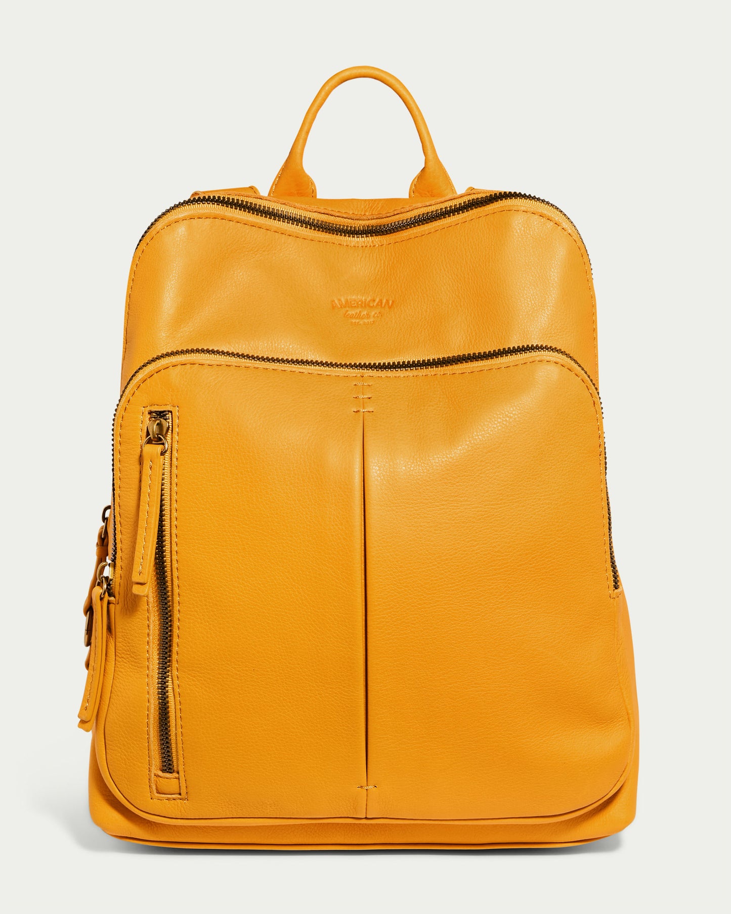 A vibrant pomegranate yellow Cleveland Backpack from American Leather Co., crafted in leather with a textured finish. This stylish backpack boasts two zippered compartments and a top handle, with the brand name embossed on the upper front for authenticity and style.