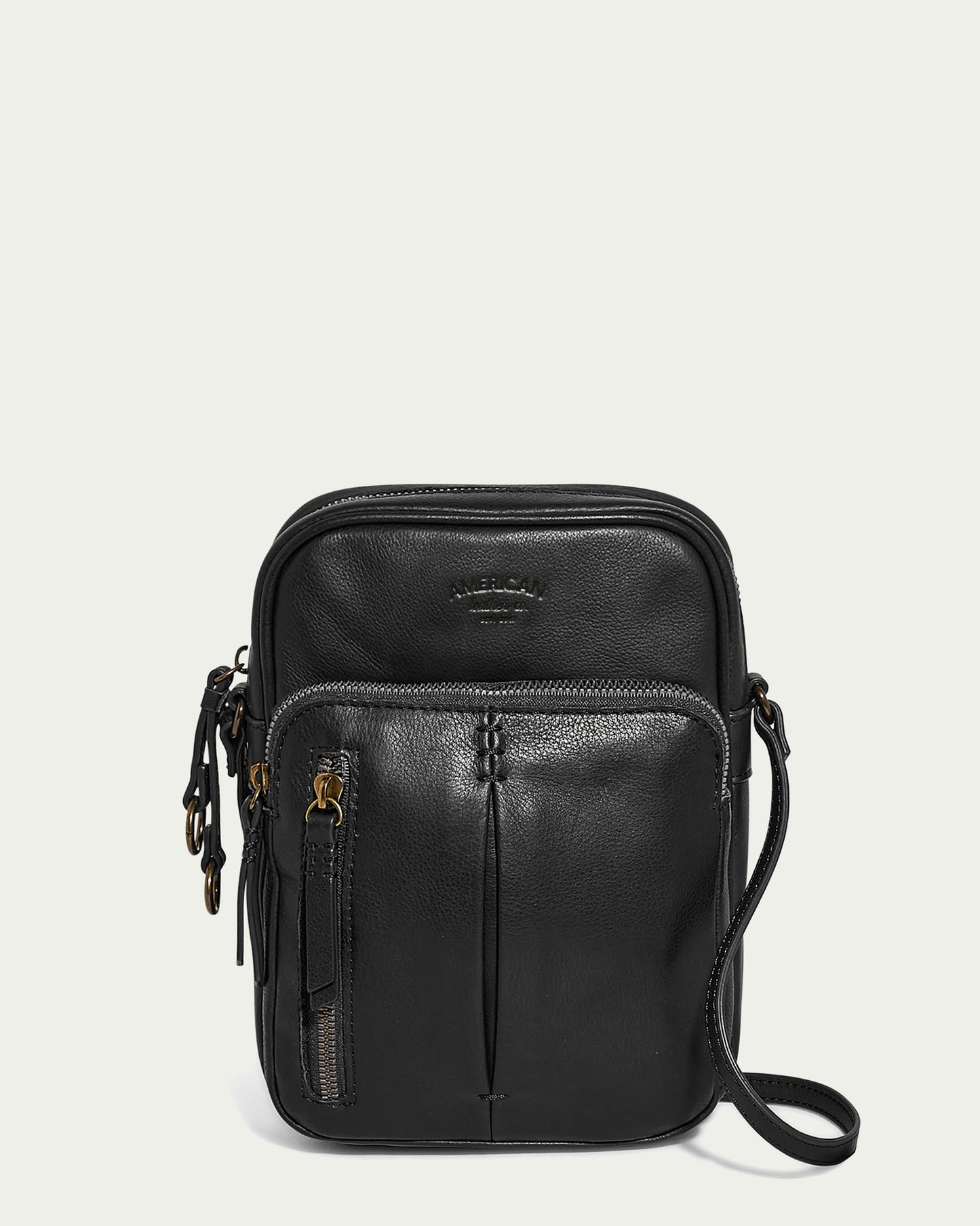 The Cleveland Large NS Crossbody from American Leather Co. is a sleek black leather crossbody bag crafted with genuine American leather. It features multiple zippered compartments, brass hardware, a front logo, and an adjustable strap, displayed against a light gray background.