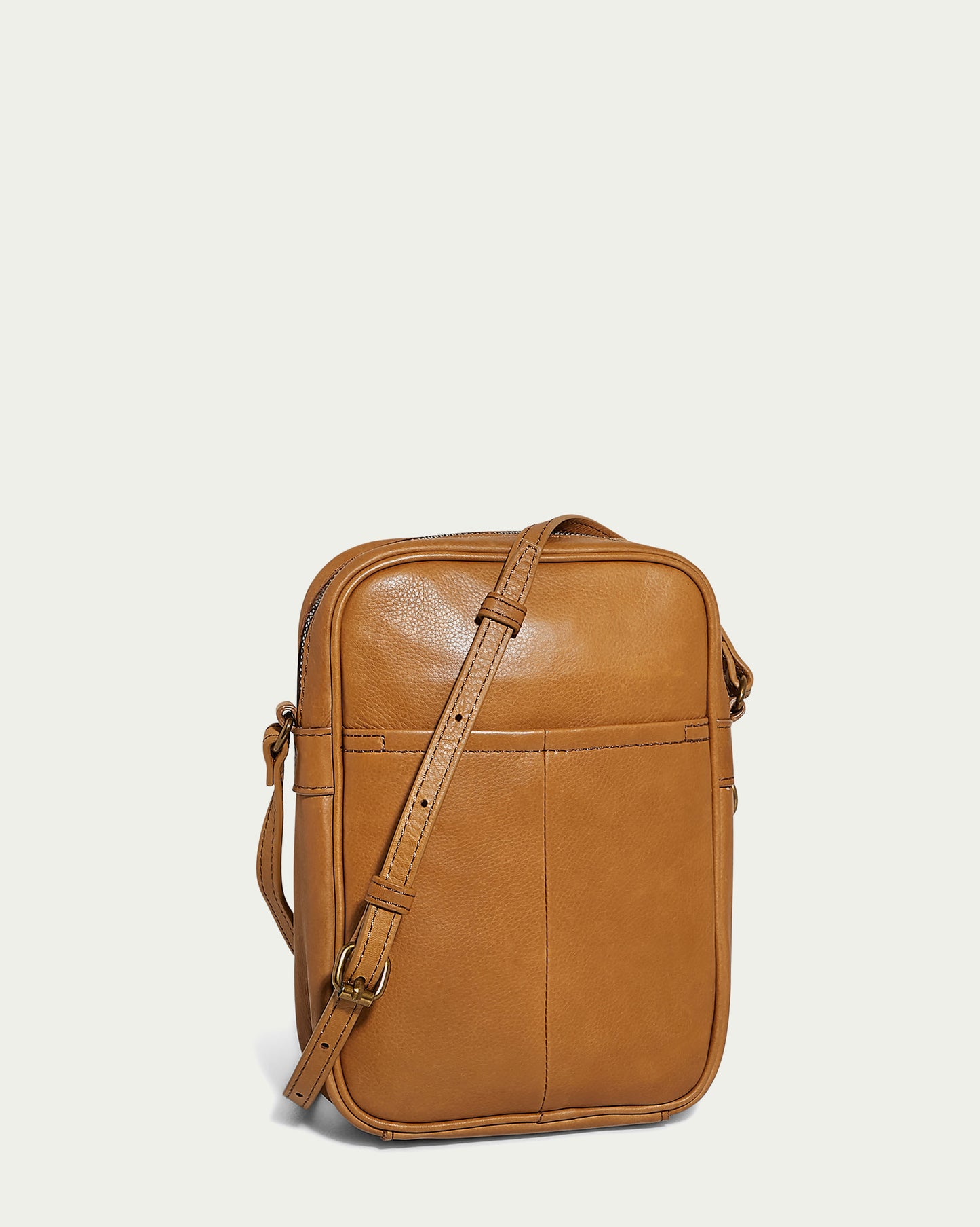 The Cleveland Large NS Crossbody by American Leather Co. is a spacious, tan leather bag crafted from Genuine American Leather. It boasts a smooth texture, an adjustable crossbody strap, and a front pocket. Set against a light background, its rectangular shape and visible stitching are strikingly prominent.