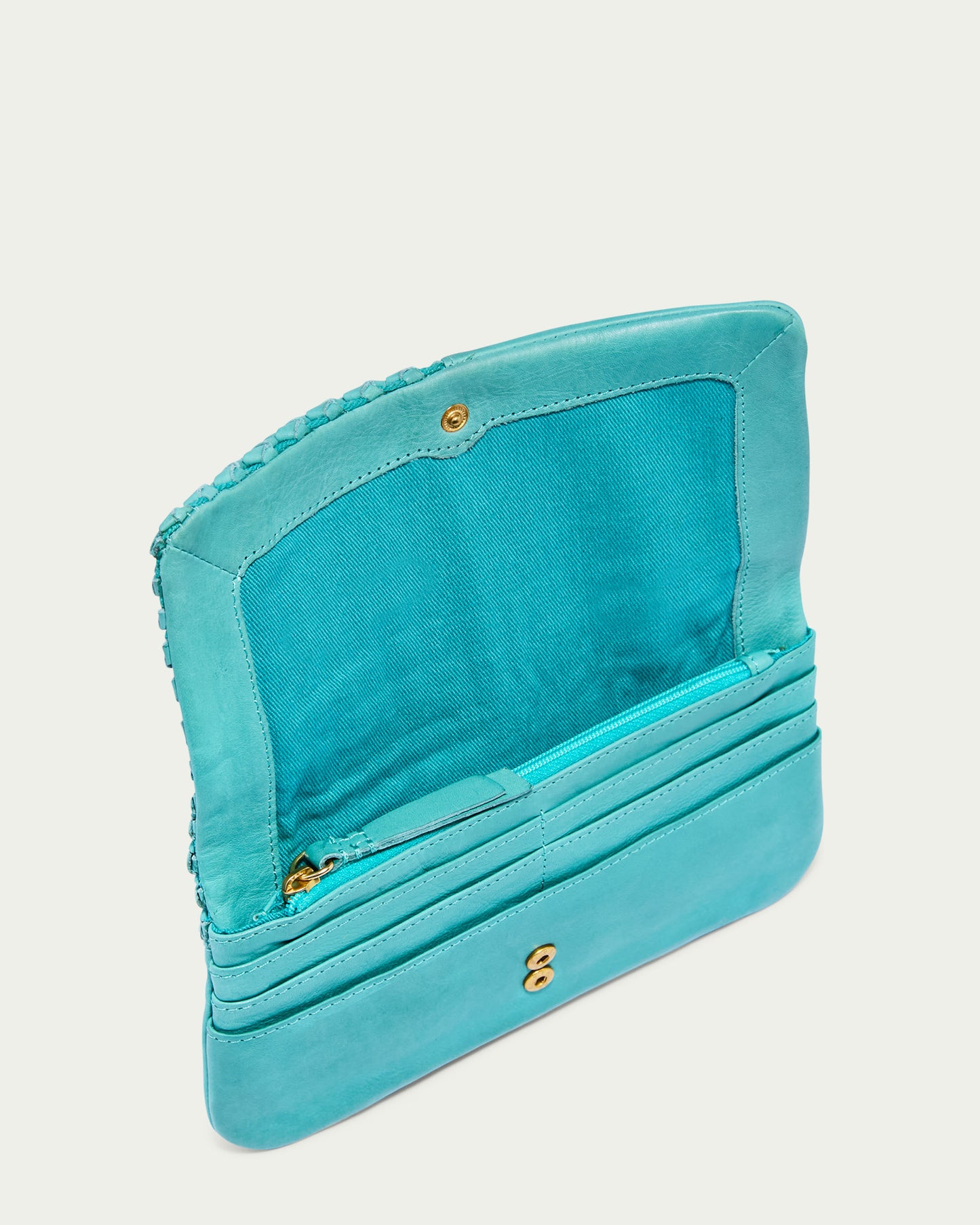 The Webster Woven Bifold Wallet in turquoise from American Leather Co. showcases a button closure that opens to reveal card slots, a zippered compartment, and a fabric lining. This sophisticated piece is crafted from soft leather with intricate woven details along the edge.