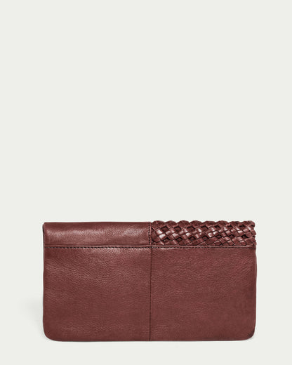 The Webster Woven Bifold Wallet by American Leather Co. is a brown leather clutch crafted from supple leather, featuring woven details on the top right section, while the rest of the wallet boasts a smooth finish. It is set against a plain light grey background.