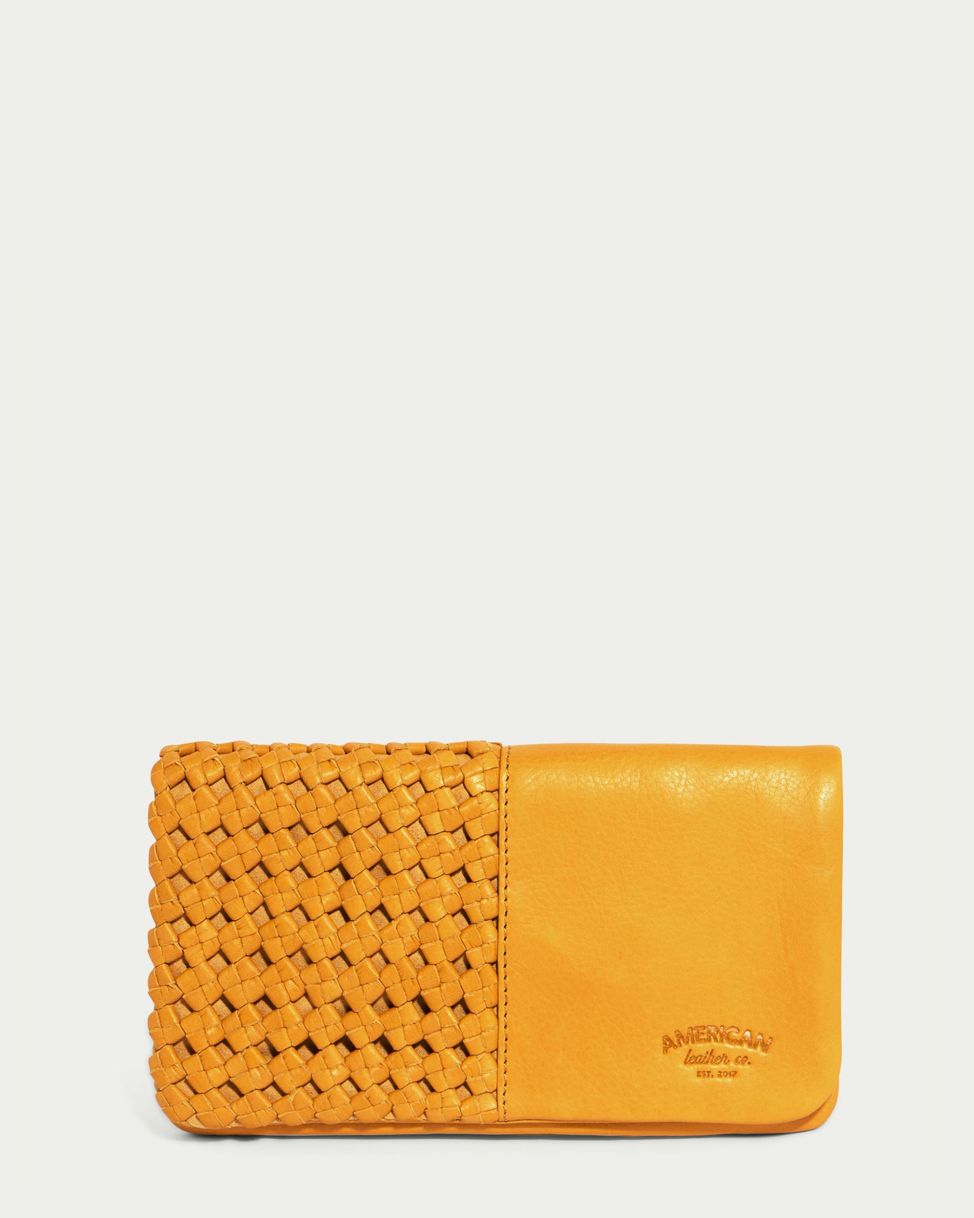 A pomegranate yellow leather bifold wallet featuring supple, woven details on one side and a smooth surface on the other. The brand "American Leather Co." is embossed on the smooth side, showcasing a perfect blend of style and craftsmanship.