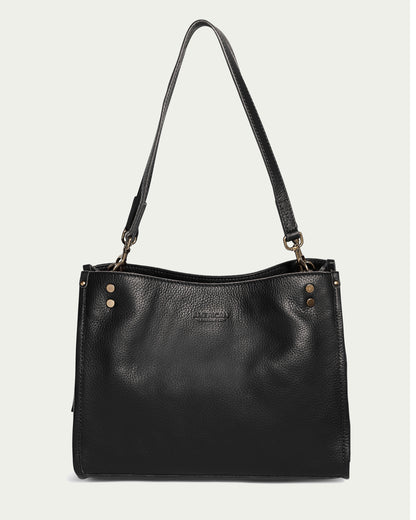 The Lenox Triple Entry Satchel by American Leather Co. is a black leather handbag crafted from genuine American leather. It includes a shoulder strap, gold-tone hardware, two visible studs on each upper side, and has a structured rectangular shape with a subtle logo embossed on the front against a light gray background—an everyday essential.