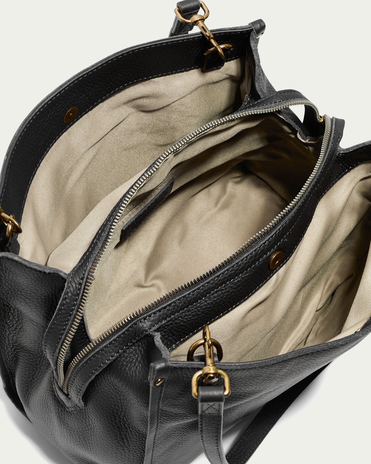 A top view of the Lenox Triple Entry Satchel from American Leather Co. showcases an open black leather bag crafted from genuine American leather, featuring a beige interior lining. It includes two interior compartments and a middle zippered pocket, making it an everyday essential. The bag is adorned with gold-tone hardware and visible stitching.