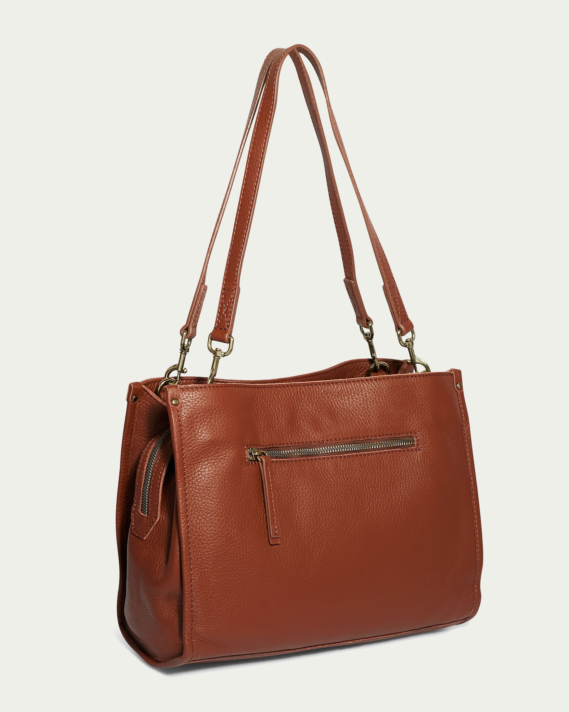 The Lenox Triple Entry Satchel by American Leather Co. is a stylish brown leather tote crafted from Genuine American Leather. It features long handles, a zippered front pocket, metal hardware, and a textured finish, displayed against a plain off-white background.