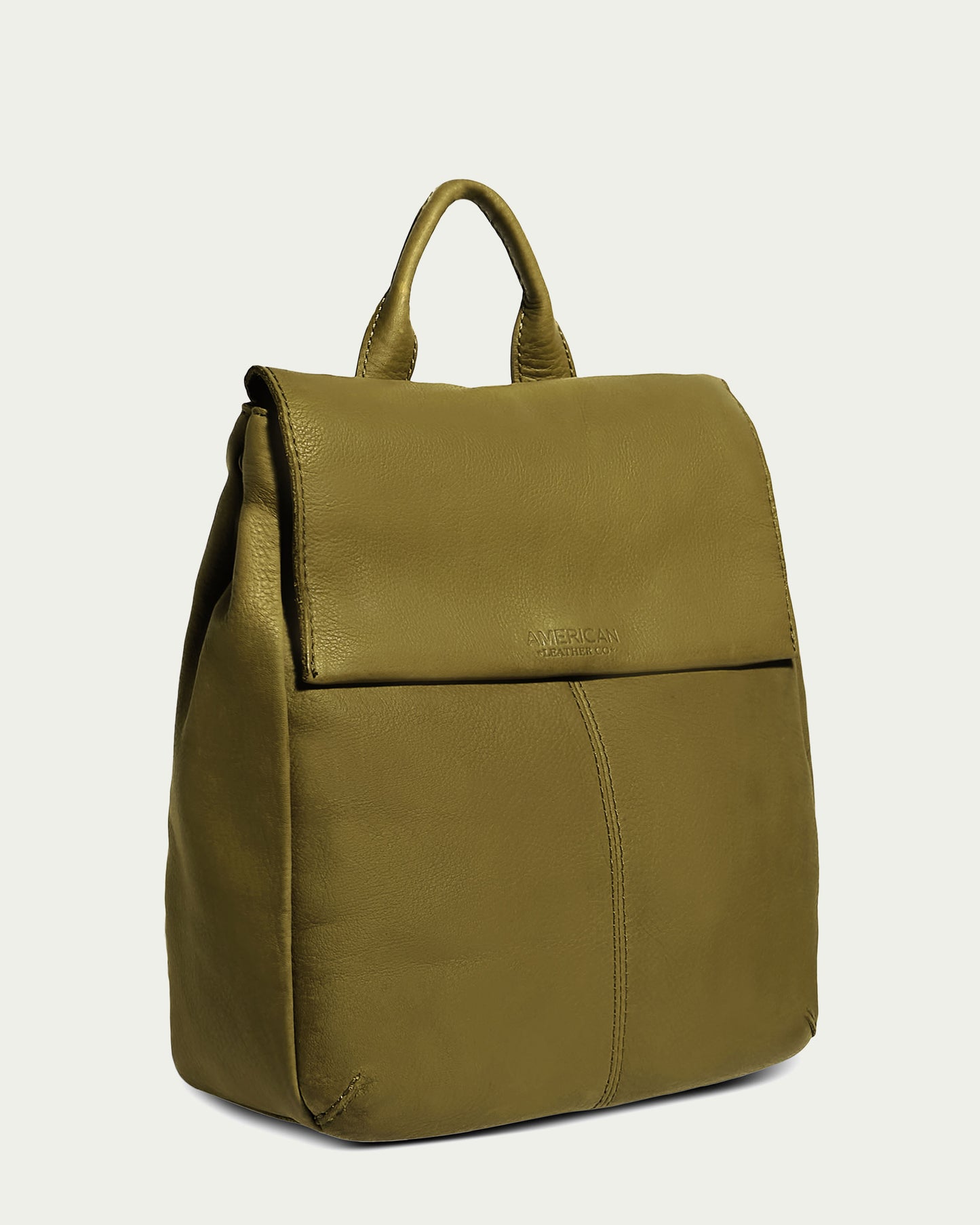 The Liberty Backpack by American Leather Co. is a women's leather backpack made from genuine American leather, featuring adjustable straps, a top handle, and a front flap for the main compartment. Its clean, minimalist design contrasts with a light green background.