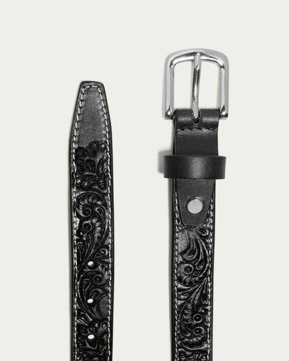 Close-up of the American Leather Co. Lockport Belt: a Western-inspired black calf leather belt with floral embossing, white edge stitching, and a silver buckle, set against a light background.