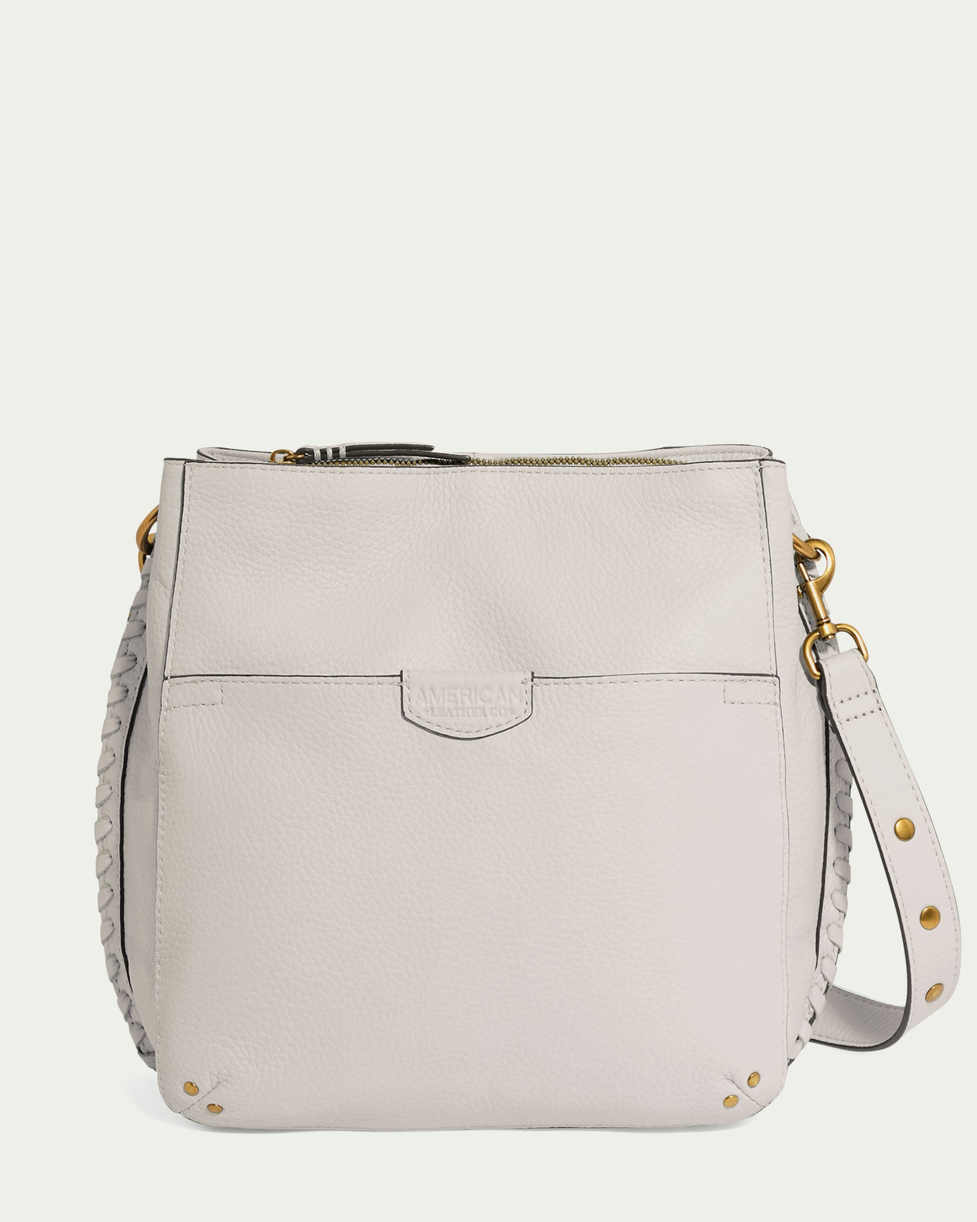 The cream-colored Luca Triple Entry Crossbody from American Leather Co. is a handbag made of glove-tanned pebble leather, designed with a gold-tone hardware and an adjustable crossbody strap. It includes a front pocket and subtle stitching that together create an aura of sleek elegance.