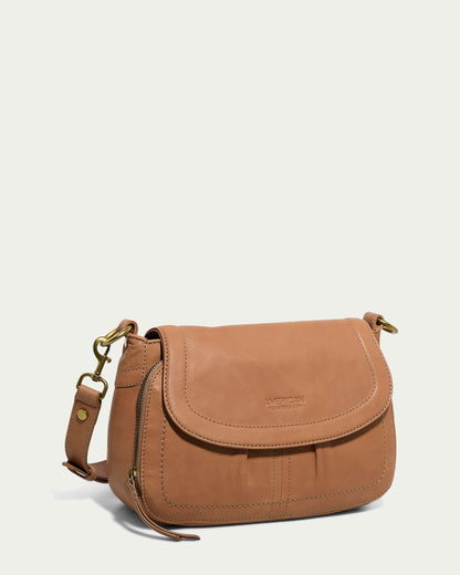 The Marino Crossbody with 2 Straps by American Leather Co. showcases a curved flap closure, a gold-tone buckle on the adjustable strap, and a front zipper pocket. Crafted from butter-soft leather, it features subtle stitching details and a smooth finish that exudes elegance.